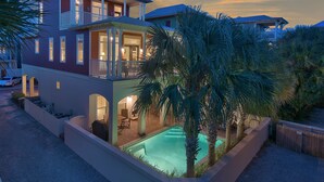 Ein zweistöckiges Haus mit Swimmingpool, Balkon und überdachter Terrasse.