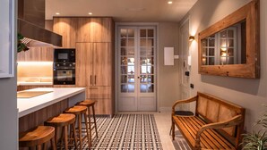 A modern kitchen with wooden cabinets, a built-in oven, and a bar area with stools. - Lovely 6 BR Flat in L Eixample (Barcelona)