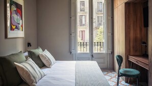 A bedroom with a bed, pillows, a chair, a desk, and a window with an open door. - Lovely 6 BR Flat in L Eixample (Barcelona)
