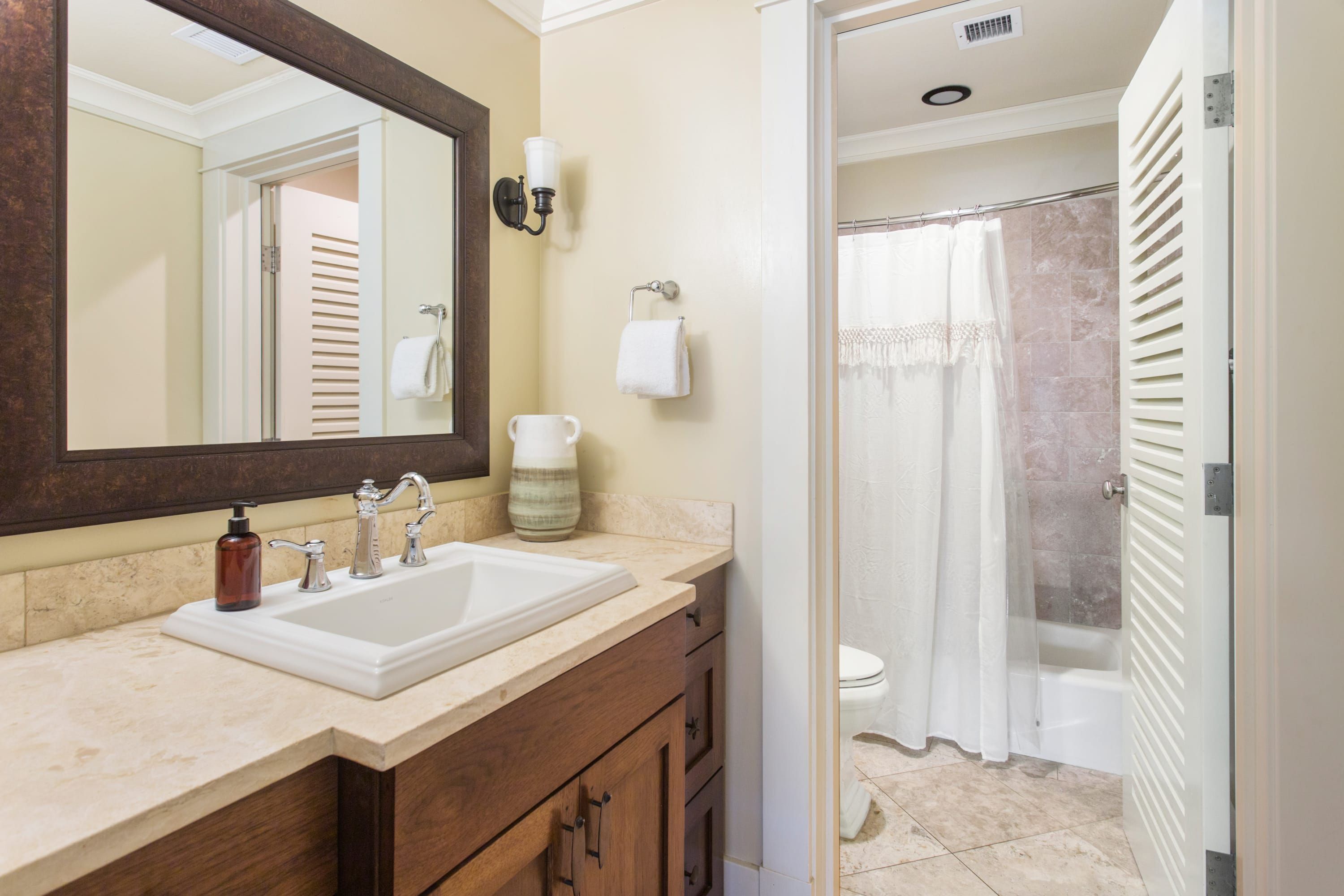 A bathroom with a sink, mirror, towel rack, and shower curtain.
