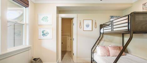 Habitación con literas, una ventana, una puerta que da a un pasillo y una alfombra estampada.