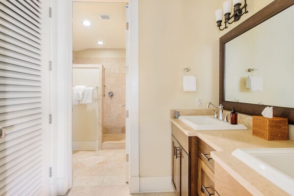 Une salle de bain avec deux lavabos, un grand miroir et un espace douche.