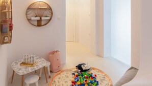 A bright, white room with a round play mat, a small table with a chair, and a wall-mounted mirror. - Modern Mykonos Villa Private Pool Stunning View (Mykonos)