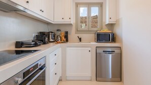 A compact kitchen with white cabinets, a built-in oven, a microwave, and a dishwasher. - Modern Mykonos Villa Private Pool Stunning View (Mykonos)