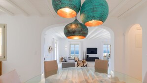 A spacious living room with a glass-top dining table, a sofa, and a TV. - Renovated Luxury Oceanview Villa With Pool in Mykonos (Mykonos)