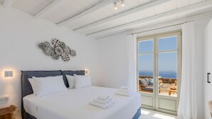 A spacious bedroom with a large bed, a decorative wall piece, and a balcony with a view. - Renovated Luxury Oceanview Villa With Pool in Mykonos (Mykonos)