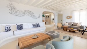 A modern living room with a white sofa, wooden coffee table, and light blue armchairs. - Renovated Luxury Oceanview Villa With Pool in Mykonos (Mykonos)
