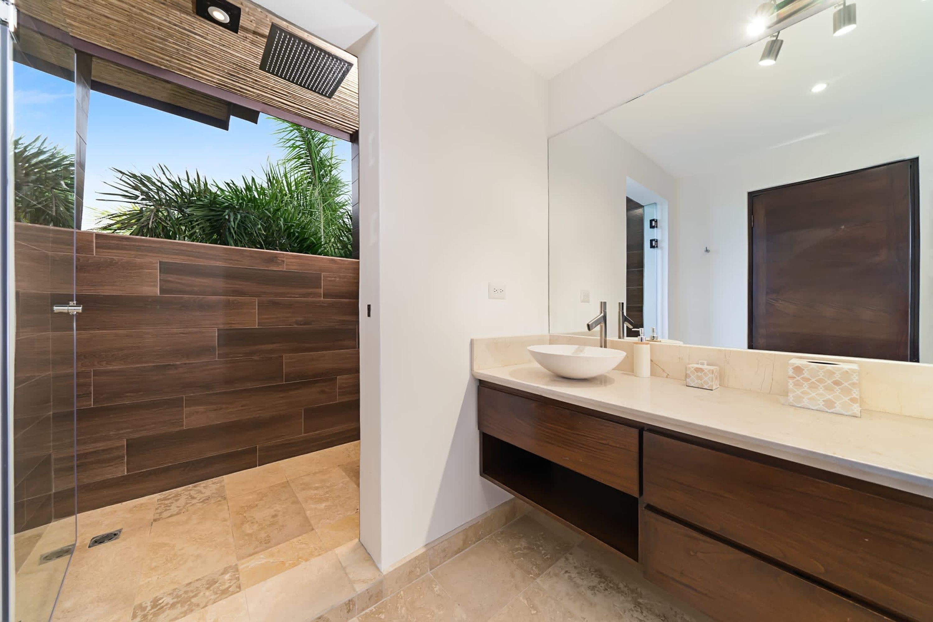 Un baño moderno con un espejo grande, un lavabo blanco y un mueble de tocador de madera.