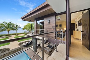Une maison moderne dotée d’une piscine, d’un espace salon extérieur et offrant une vue sur l’eau.