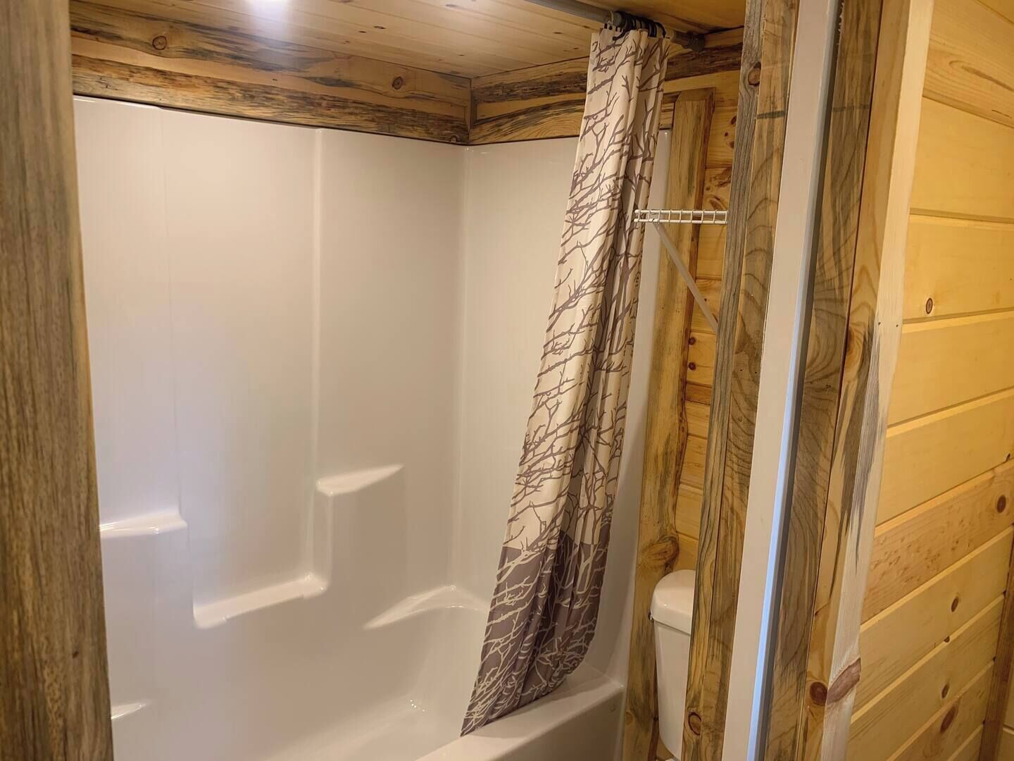 A wooden cabin bathroom with a shower and toilet.