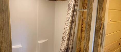 A wooden cabin bathroom with a shower and toilet.
