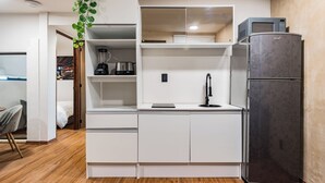 A compact kitchen with white cabinetry, a built-in microwave, a refrigerator, and a sink with a modern faucet.