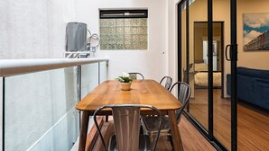 A dining area with a wooden table, metal chairs, a potted plant, and a window with a decorative grille.