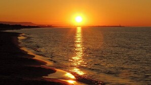 A sunset over a calm sea with a beach in the foreground. - B&B LA PERLA NERA (Fasano)