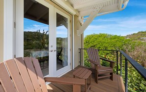 A wooden deck with two chairs and a table, overlooking a lush green landscape. - The Pirate's Landing North - St. John USVI - Chocolate Hole (Cruz Bay)
