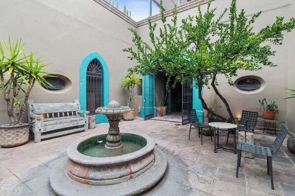 A courtyard with a fountain, a bench, and potted plants.