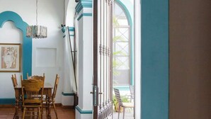 A room with a dining table and chairs, a chandelier, and a view through an open door to an outdoor area. - Unique Suite Historic Center Terrace WIFI+Desk+AC (Santiago de Querétaro)