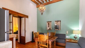 A dining area with a wooden table and chairs, a sofa, a chandelier, and a tiled floor.