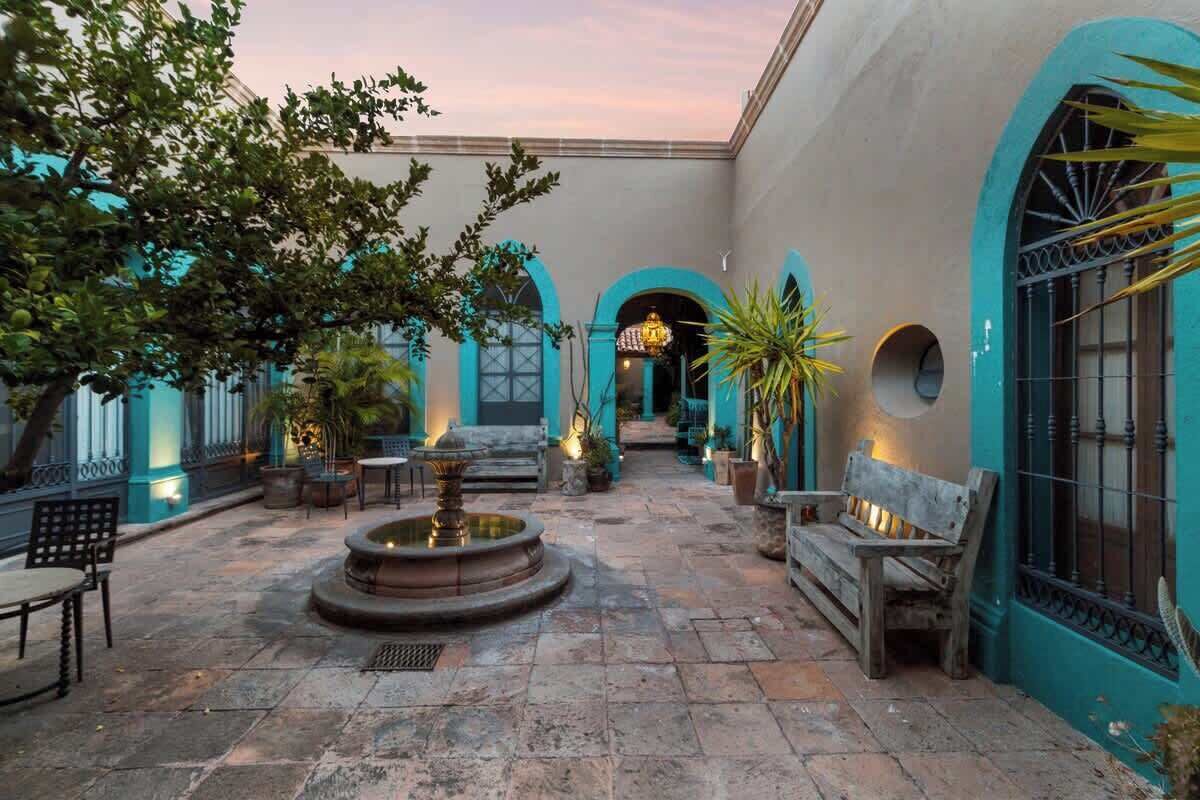 A courtyard with a fountain, benches, and potted plants.