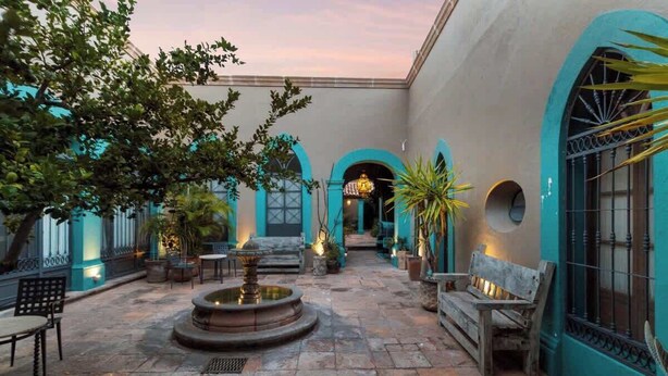 A courtyard with a fountain, benches, and potted plants.