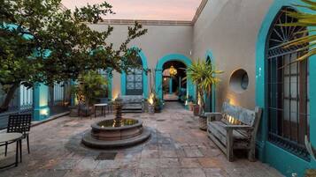 A courtyard with a fountain, benches, and potted plants.