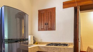 A kitchen with a stainless steel refrigerator, wooden cabinets, a countertop, and a tiled floor.