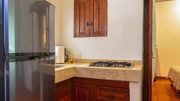 A kitchen with a stainless steel refrigerator, wooden cabinets, a countertop, and a tiled floor.