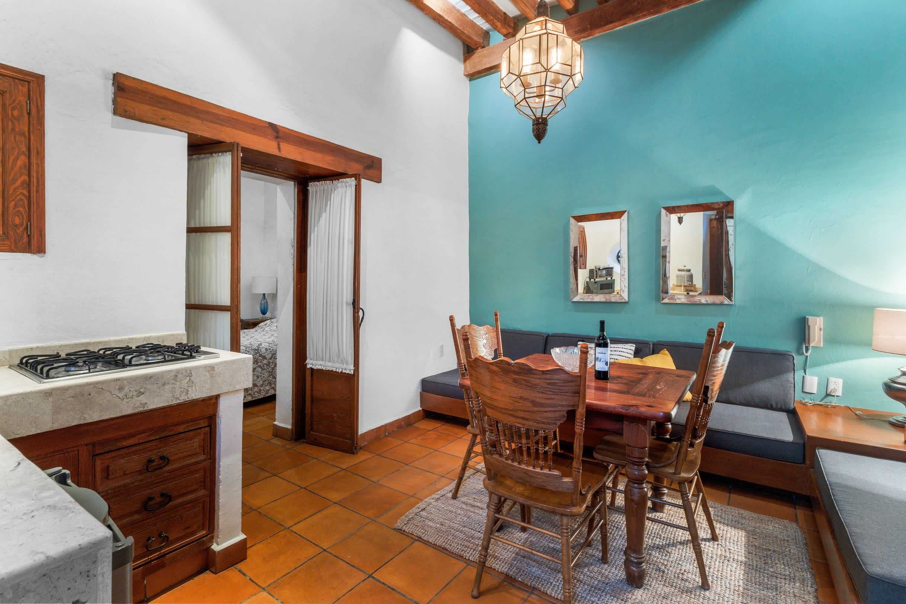 A compact kitchen with a gas stove, wooden cabinets, and a dining area with a table and chairs.