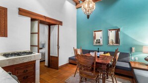 A compact kitchen with a gas stove, wooden cabinets, and a dining area with a table and chairs.