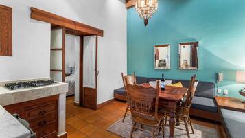 A compact kitchen with a gas stove, wooden cabinets, and a dining area with a table and chairs.