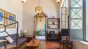 Een gezellige woonkamer met een bank, een houten tafel, een bureau en een boekenkast.