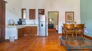 A kitchen with a refrigerator, wooden cabinets, a glass table, and a dining area with chairs. - Suite on main street in Historic Downtown WIFI (Santiago de Querétaro)