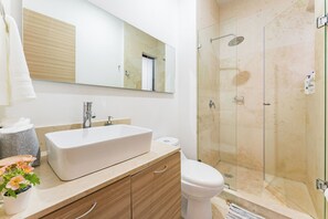 A modern bathroom with a large mirror, a white sink, a toilet, and a glass-enclosed shower. - NEW Perfect Location with Free Parking (Mexico City)