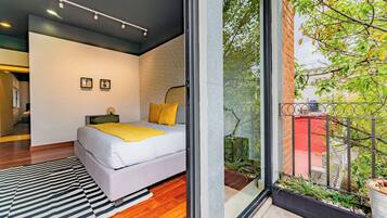 A modern bedroom with a large bed, a black and white striped rug, and a view of a garden through a glass door.