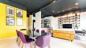 A modern living room with a glass dining table, purple chairs, a yellow sofa, and a TV on a shelf. - NEW Perfect Location with Free Parking (Mexico City)