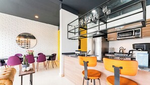 A modern kitchen with a brick wall, wooden cabinets, and a glass shelf holding wine glasses. - NEW Perfect Location with Free Parking (Mexico City)