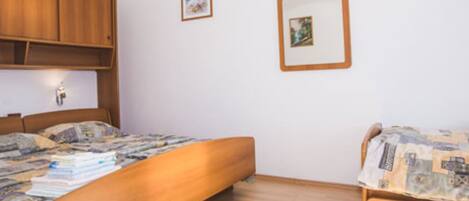A bedroom with a wooden bed, a wooden wardrobe, and two framed pictures on the wall.