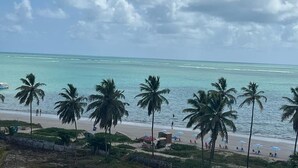 A beach with palm trees, a sandy shore, and a clear sky. - Pé na Areia em Ponta de Campina, Paraíba (Cabedelo)