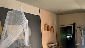 Un dormitorio moderno con una cama grande, una mesita de noche, una silla y vistas al baño.