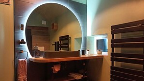 Un baño con tocador de madera, un perchero, un espejo y una toalla colgada en la pared.