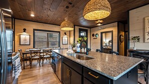 A kitchen with a granite countertop, wooden cabinets, and a central island. There are hanging lights, a refrigerator, and a sink. - Minutes to Parkway! 3600 Sq Ft Cabin w/ Waterpark & Mountain View’s (Sevierville)