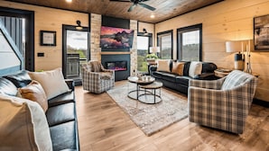 A cozy living room with a fireplace, two sofas, a coffee table, and a ceiling fan. - Minutes to Parkway! 3600 Sq Ft Cabin w/ Waterpark & Mountain View’s (Sevierville)