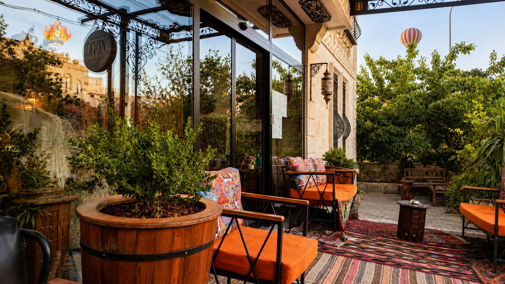 An outdoor seating area with wooden furniture, potted plants, and a patterned rug.
