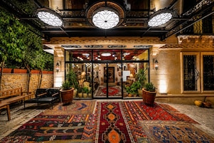 Un hall d’entrée doté d’un tapis à motifs, de bancs en bois et d’un escalier menant à un niveau supérieur.