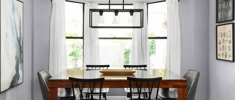 Un comedor con una mesa de madera, sillas negras y una lámpara colgante moderna.