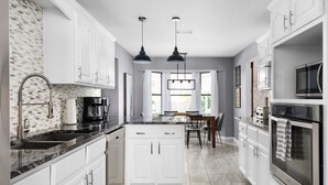 A modern kitchen with white cabinets, a granite countertop, a built-in oven, and pendant lighting. - HOT TUB Tranquil Escape Pool Gym (Round Rock)