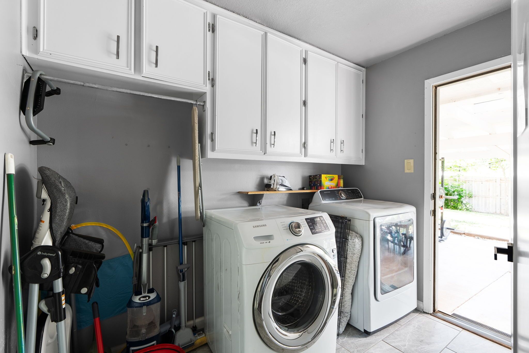 A laundry room with two washing machines, a drying rack, and cleaning supplies.