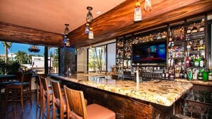 A bar area with a wooden ceiling, a marble countertop, and a TV screen.