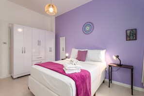 A bedroom with a bed, a bedside table with a lamp, a wardrobe, and a wall decoration.