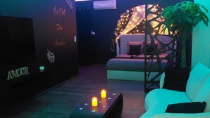Un espacio lounge moderno con un sofá, una mesita con velas y una pared decorativa con texto.